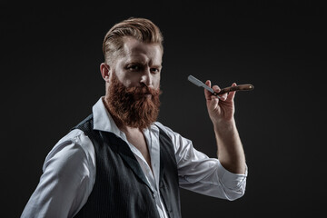Bearded hipster barber isolated on black. Man beard haircut by hairdresser at barbershop. Handsome barber using retro blade while cutting hair. Modern barbershop haircut. Stylish haircut