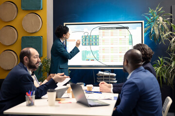 Business consultant gathering his staff members for a status update meeting in conference room, interactive presentation with the latest reports. Success metrics and key performance indicators.