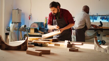 Carpenter in assembly shop starting renovation project on timber block, applying lacquer on surface. Woodworking specialist coloring wood plank with paintbrush, enjoying diy hobby, camera B