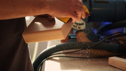 Manufacturer working in joinery using sanding block to remove imperfections on wood piece. Woodworking specialist using coarse grade sandpaper to do manual sanding on lumber, camera A close up