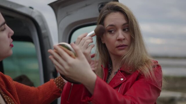 The photographer helps the model to put on her makeup