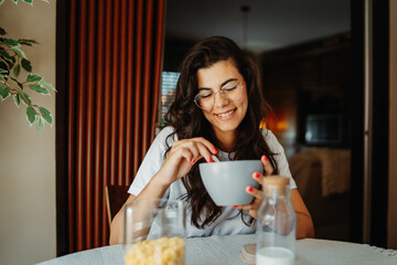 Young caucasian woman eating corn flakes for breakfast