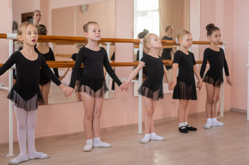 Fototapeta premium Children's ballet school. Caucasian woman teaching ballet to little girls. 