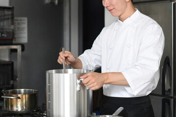 厨房で料理を作る若いアジア人の男性調理師