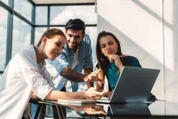 Obraz premium Group of diverse profession business people pointing at laptop displayed idea. Portrait of business team show marketing strategy present by laptop with statistic document scatter on table. Tracery.