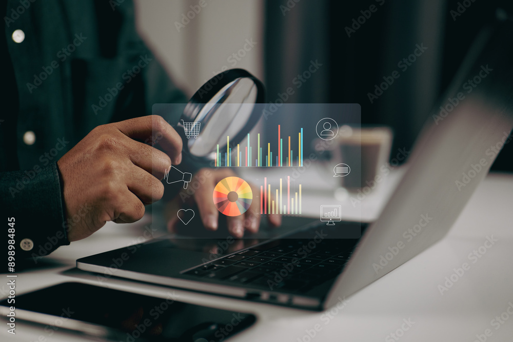 Fototapete Person using a magnifying glass to examine data visualizations on a laptop. It represents the importance of detailed analysis and scrutiny in data-driven decision-making processes