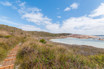 Marvel at the rugged beauty of Two Peoples Bay, Australia. This view captures pristine turquoise waters, rocky shores, and majestic hills, offering a serene escape into nature's untouched landscapes.