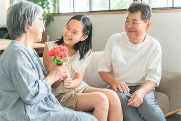 祖父母に敬老の日のお祝いに花束をプレゼントする孫・女の子
