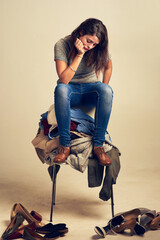 Fashion, bored and woman with pile of clothes on chair for mess, clutter or collection. Doubt,...