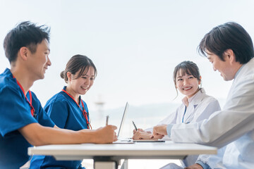 医局でカンファレンス・打ち合わせ・ミーティングする男女の医師・医者・看護師・医療従事者・技師
