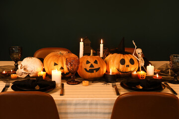 Festive table setting for Halloween celebration with pumpkins and burning candles at evening