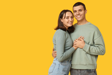 Fototapeta premium Cheerful young couple hugging on yellow background