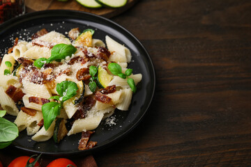 Tasty pasta with bacon and basil on wooden table, space for text