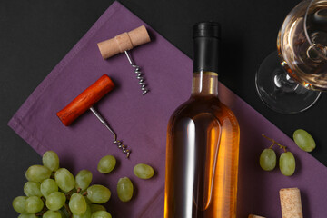 Corkscrews, wine and grapes on black background, flat lay