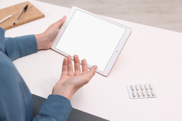 Sick woman having online consultation with doctor via tablet at white table indoors, closeup
