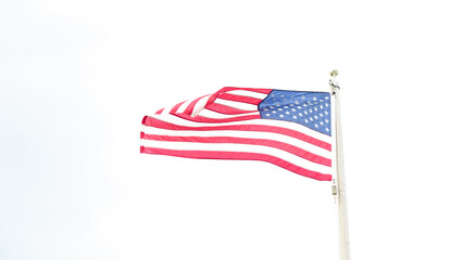 Fototapeta premium Beautiful American flag waving in the wind, with vibrant red white and blue colors against blue sky, with copy space.