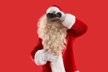 Santa Claus looking through binoculars on red background