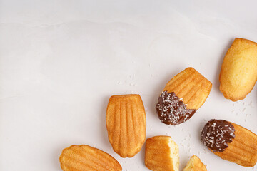 Delicious madeleines with chocolate cream and coconut flakes on white background