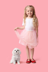 Cute little girl with Maltese dog on pink background