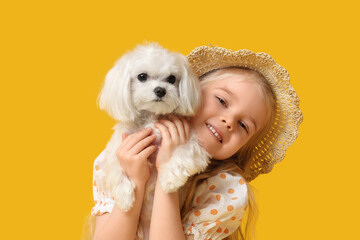 Cute little girl with Maltese dog on yellow background