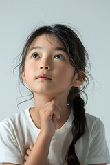 Little child thinking with hand on chin wearing t-shirt in studio on white background