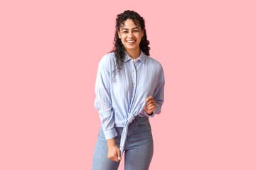 Happy young African-American woman in stylish blue collar shirt on pink background