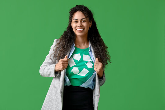 Beautiful young African-American businesswoman in t-shirt with recycling symbol on green background