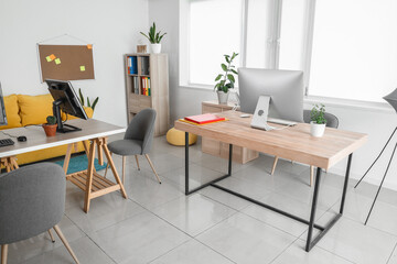 Interior of stylish office with modern workplaces and shelf unit