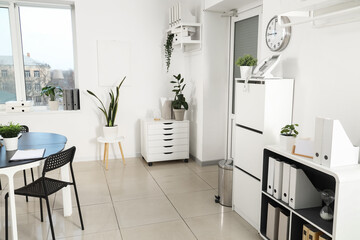 Interior of modern office with door, plants and drawers