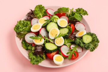 Plate of tasty salad with boiled quail eggs and vegetables on pink background