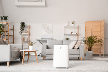 Modern humidifier and grey sofa in stylish living room