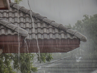 Rain water gushes down off of rooftops of residential houses during a heavy storm