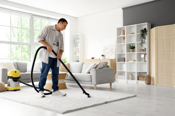 Young man cleaning carpet at home