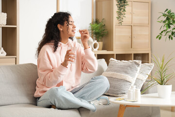 Young African-American woman taking fish oil at home