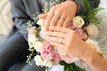Newlyweds with rings and flowers on their wedding day, closeup