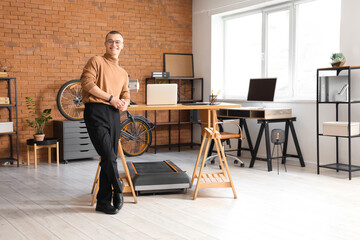 Young businessman near treadmill in office