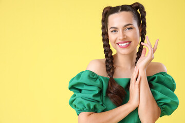 Beautiful young happy stylish woman with braids on yellow background