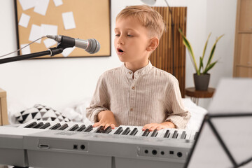 Cute little boy with modern synthesizer and microphone singing at home