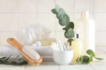 Composition with cosmetic products, bath supplies and eucalyptus branches on light tile background