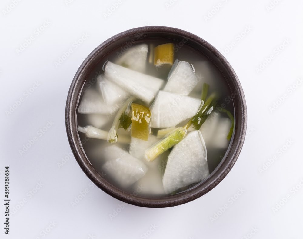 Wall mural Close-up of Dongchimi(radish water kimchi) with cut radish and leaves on black bowl, South Korea
