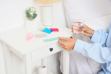 Young woman with condoms in bedroom