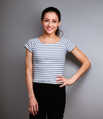 Happy toothy smiling young woman posing on blue sporty cotton t-shirt and bicycle black shorts on blue studio background. Closeup