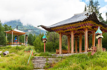 Naklejka premium Siberia, Buryatia. Park area in the resort village of Arshan with an oriental gazebo and a sculpture of medical Buddha on a hill in the foothills of the Tunka Valley on a foggy summer day