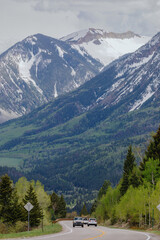 Cars driving on a county road with a snowy mountain range in the background. Carbondale, Colorado, United States of America.