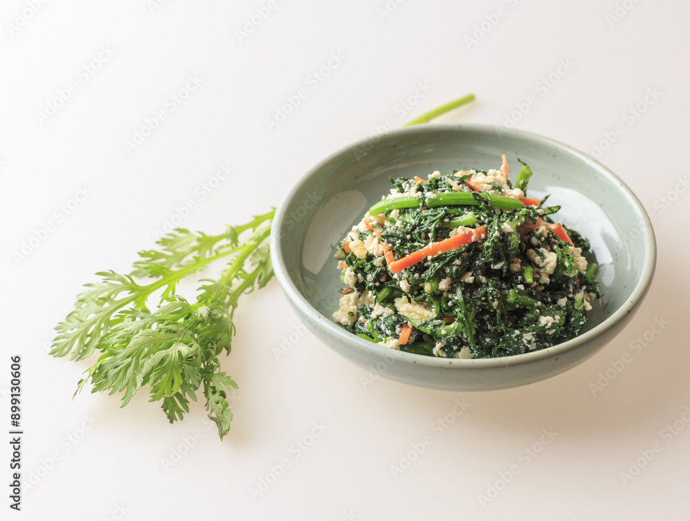 Wall mural Close-up of seasoned crown daisy with tofu and carrot on a dish with fresh leaves on white floor, South Korea
