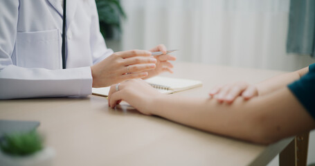 Selective focus hands of Asian doctor examines sore arm and give advice of young female patient in clinic office, Health and medicine consultant, conversation about healthcare