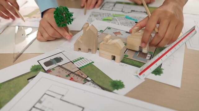 Architects determine position of tree or house using building blueprint on messy table with architectural project and measurement tool scattered around. Business and environment concept. Delineation.
