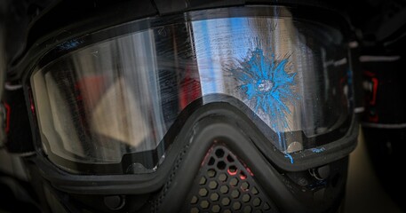 High resolution image of an isolated close up of a paintball black mask and goggles that was hit by a single blue paint ball during practice- Israel © Oren