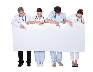 Diverse medical team holding up blank banner for advertisement. Doctor, nurse