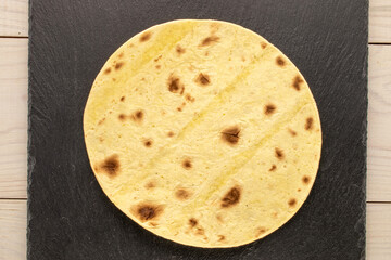 One tasty taco with slate stone on wooden table, macro, top view.